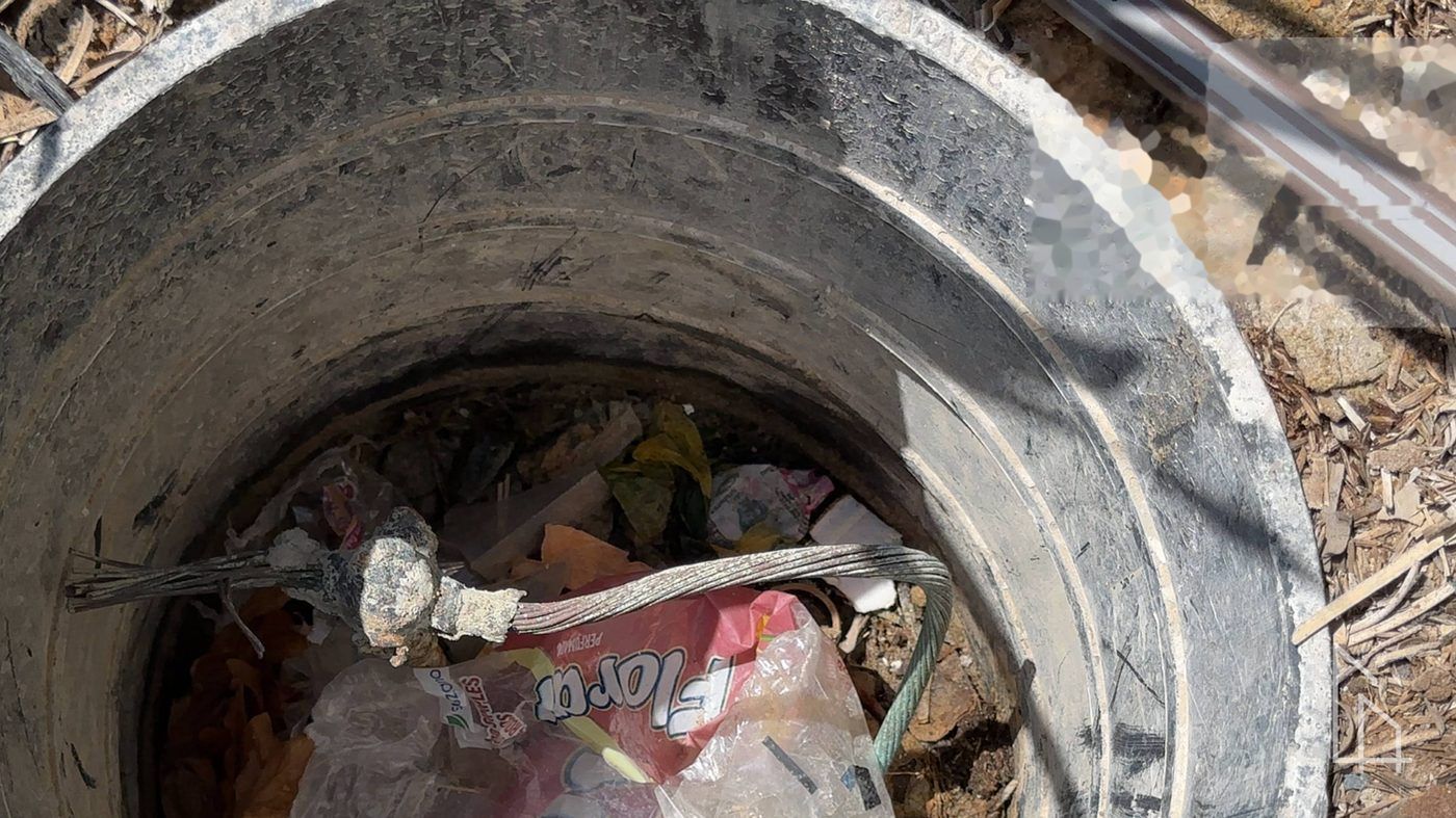 Caixa de passagem com entulho e resíduos de obra